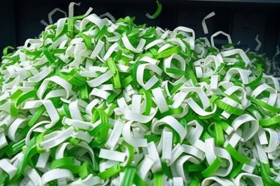 polyethylene recycling, sorted material, being shredded, photorealistic, industrial shredding plant, highly detailed, motion blur on the fast-moving blades, harsh studio-like lighting, shot with a 50mm lens.